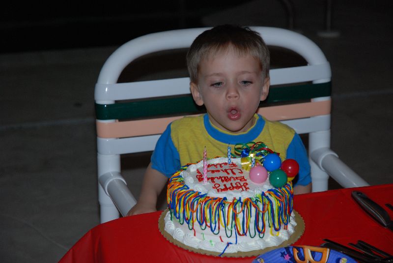 Félix soufflant les bougies décorant son gâteau d'anniversaire.