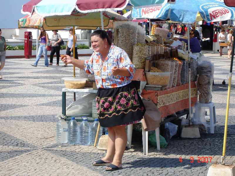 Portugaises vêtues en costume typique de Nazaré y va d’une révérence pour nous attirer à son kiosque, Nazaré, Portugal.