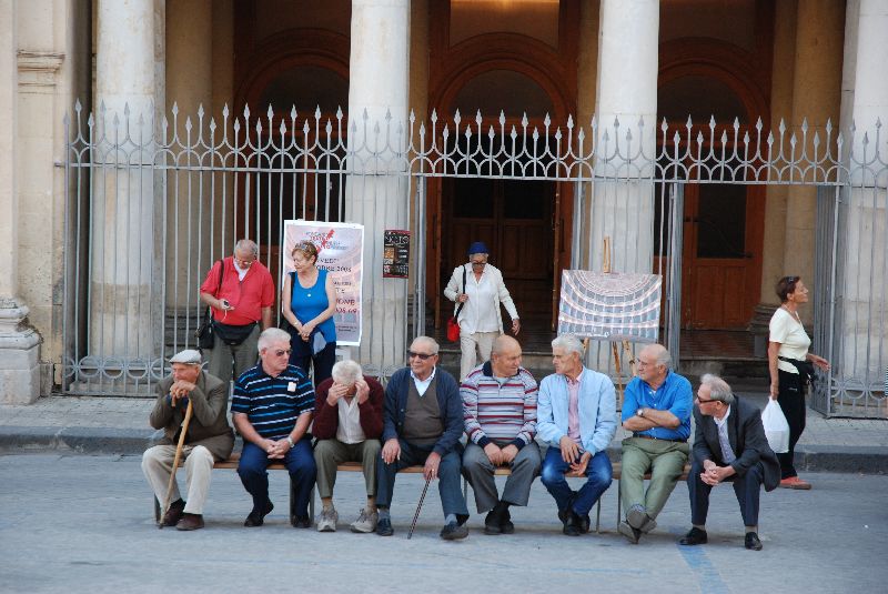 Huit Siciliens bavardant sur un banc à Noto, Syracuse, Italie.